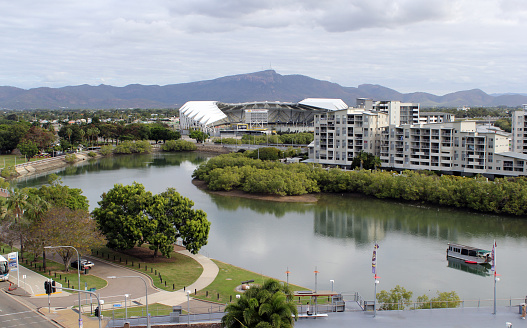 Townsville, Queensland, Australia - July 30, 2023: View of Ross Creek, trees, mangroves, buildings and Queensland Country Bank Stadium in the background