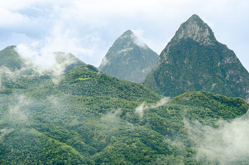 lush green misty cloud patched mountain landscape with pitons in the background - saint lucia