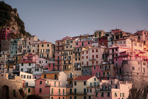 A picturesque row of houses in varying shades of pink perched atop a steep hillside in a quaint town