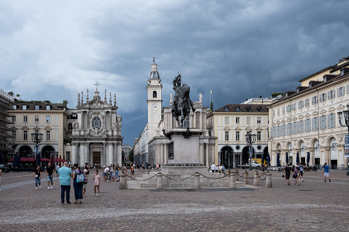 Turin, Italy – August 2023 – View of Piazza San Carlo, a central square renowned for its Baroque architecture, featuring the equestrian monument of Emmanuel Philibert in the foreground. The 1838 monument by Carlo Marochetti is situated at the center, surrounded by porticos designed by Carlo di Castellamonte around 1638.