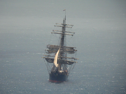 Old warship sailing the sea at dawn.