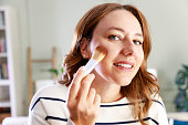 Young woman using a makeup brush on her face