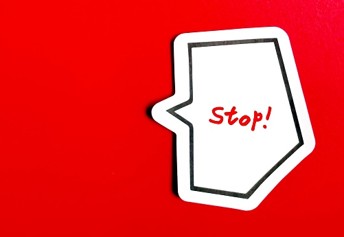 Note stick on red copy space background with handwritten word STOP!, concept of thought stopping, to remind self to notice negative thinking and redirect mind to positive one