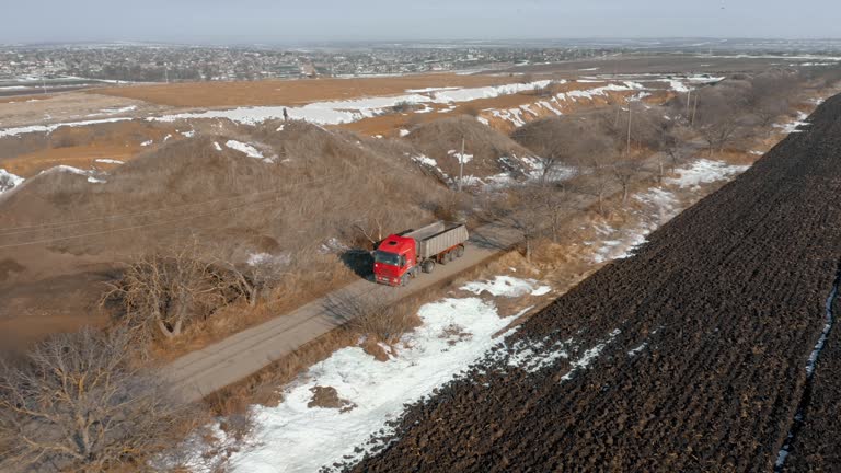 Red truck driving along the road between the hills and the field