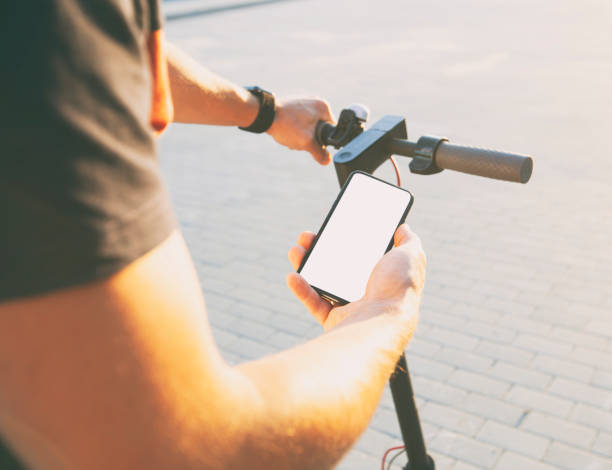 istock Man standing with electric scooter and showing the phone with blank white screen 1884235227