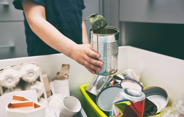 istock The boy is throwing the metal garbage to the one of four different bin for sorting trash. 1884244002
