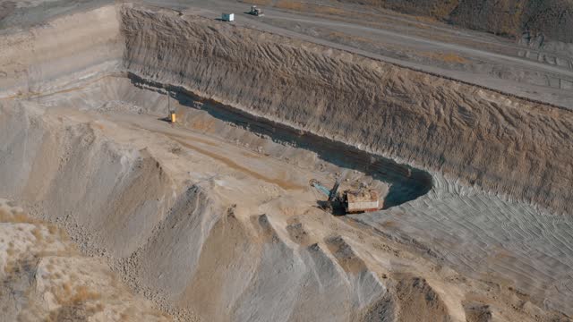 Top view of a quarry in which an excavator extracts sand