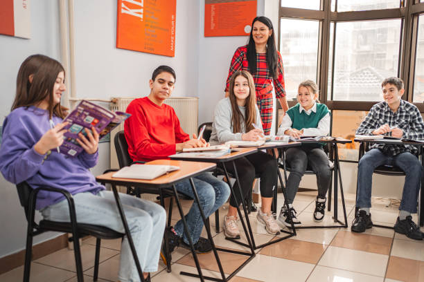 istock Female elementary student reading text in front of her classmates at language school 1884269236