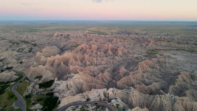 A high-flying, 4K drone shot of the sharply eroded buttes of the Badlands National Park, near Rapid City in Southwestern South Dakota, U.S.A. The camera slowly reverses and rotates to the left.