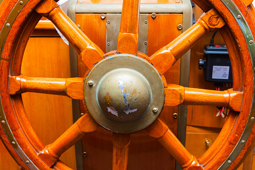 Wooden, vintage steering wheel on a yacht, close-up.