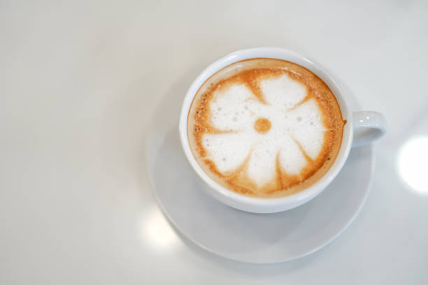 Hot latte coffee with latte art in the white cup on the white background. Copy space.