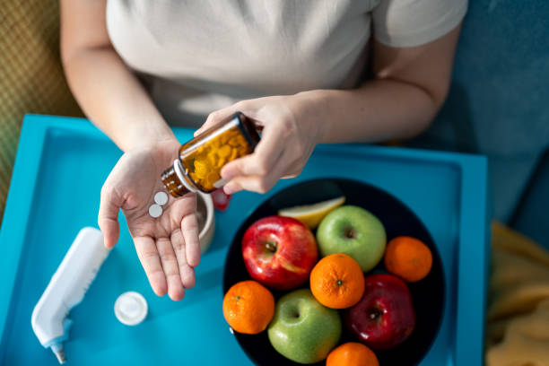 focus on the hands of unrecognizable sick woman taking medications - painkiller thermometer tea prescription medicine imagens e fotografias de stock