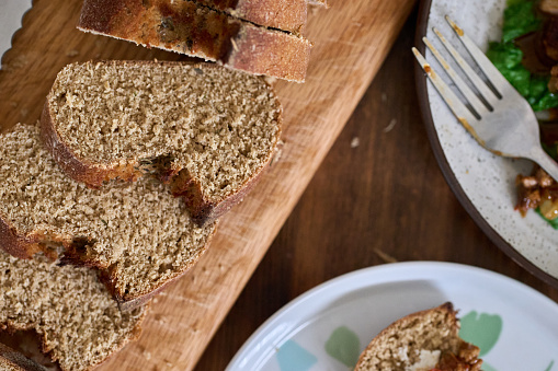 Whole grain rye bread with seeds cut into bread slices on wooden board, top view