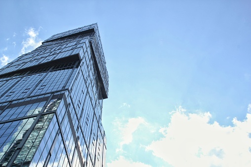 Low angle view of modern skyscraper in Hong Kong. Office building in city on blue sky background. Central Business District. Glass commercial skyline building in Moscow City