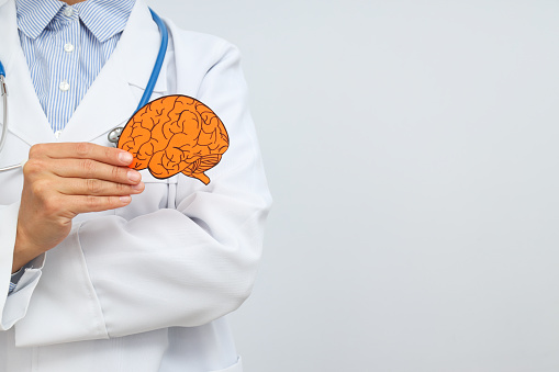 A young female doctor holds a paper human brain in her hand. Place for text