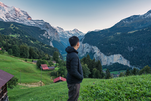 Male tourist enjoying in Wengen mountain village with Lauterbrunnen valley and Jungfrau mountain in the evening at Canton of Bern, Switzerland