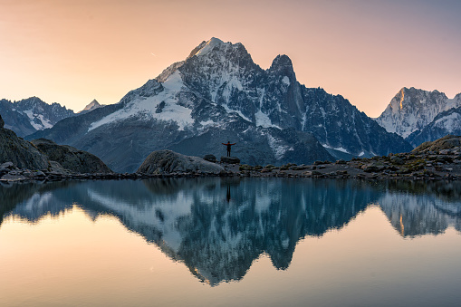 Majestic French alps landscape of Lac Blanc with Mont Blanc massif with male traveler reflected on the lake in the sunrise at Haute Savoie, Chamonix, France