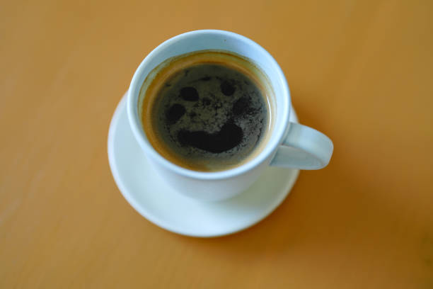 A cup of black coffee on and yellow background. Top view with copy space.