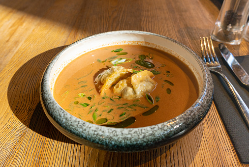 Nepalese Momo Jhol Achar Dumpling Soup, Fried Gyoza Broth, Spicy Tomato Momo Seasoned Soup in Exquisite Serving Restaurant Bowl in Sunlight Closeup