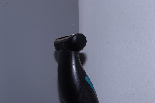 A Razor shaving trimmer standing in the corner of a grey wall