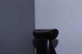 A Razor shaving trimmer standing in the corner of a grey wall, closeup