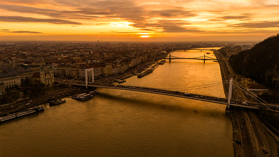 An Aerial Drone Unveils the Elisabeth Bridge and Szechenyi Chain Bridge Over the Danube River Amidst Budapest's Cityscape During Sunset. Hungary's Capital Transforms Into a Picturesque Canvas,Blending Architectural Splendor and Natural Beauty in a Captivating Display of Colors