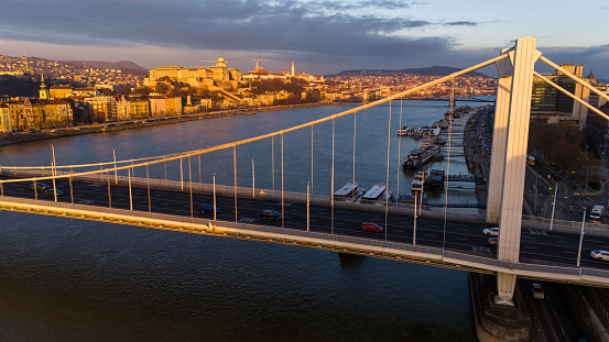 From a High Angle Drone Perspective,Witness the Rhythmic Flow of Cars on Elisabeth Bridge Over the Danube River During the Enchanting Sunset in Budapest,Hungary. The Cityscape Transforms into a Glowing Panorama