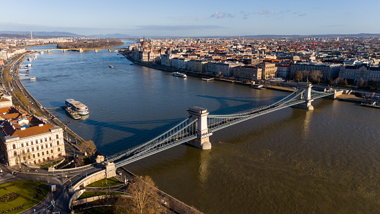 From the Bird's-Eye View of a Drone,the Szechenyi Chain Bridge Gracefully Spans the Danube River,Weaving Through the Heart of Budapest,Hungary. Bathed in Sunlight,the Iconic Bridge Stands as a Symbol of Architectural Elegance