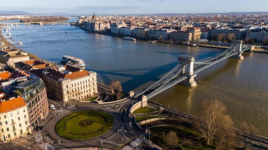 Captured From a Soaring Drone Perspective,the Szechenyi Chain Bridge Spans the Danube River,Seamlessly Integrating Into the Picturesque Cityscape of Budapest,Hungary. The Sun Drenched Scene Showcases the Architectural Grandeur of the Bridge Embodying the Vibrant Spirit of this Historic and Charming City
