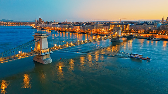 Illuminated Beauty From Above,an Aerial Drone View Captures the Szechenyi Chain Bridge Over the Danube River,Adorned with Lights,and the Budapest Parliament Building in the Background at Night. A Stunning Perspective of Hungary's Capital