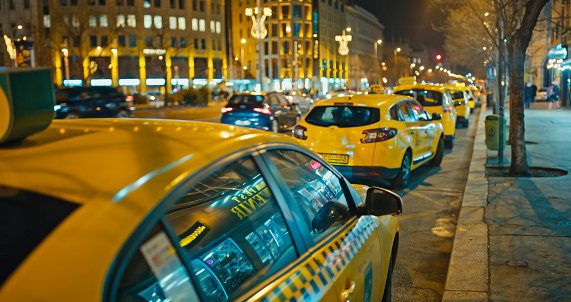 Festive Taxi Lineup,Taxis Parked in a Row on an Illuminated City Street at Night During Christmas in Budapest,Hungary. The Scene Captures the City's Holiday Spirit,Blending Urban Lights with Seasonal Charm