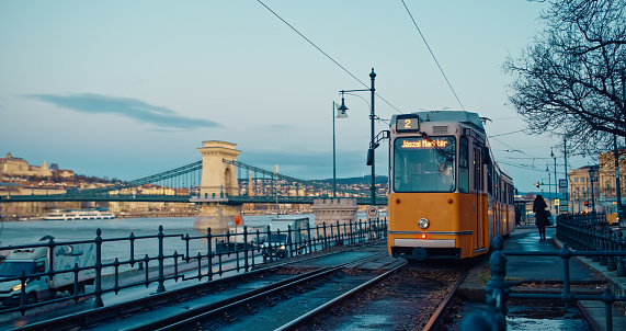A Tram Gracefully Moves on Railroad Tracks Along the Szechenyi Chain Bridge Against the Evening Sky at Dusk in Budapest,Hungary. The Scene Captures the City's Dynamic Energy as Day Transitions into Night