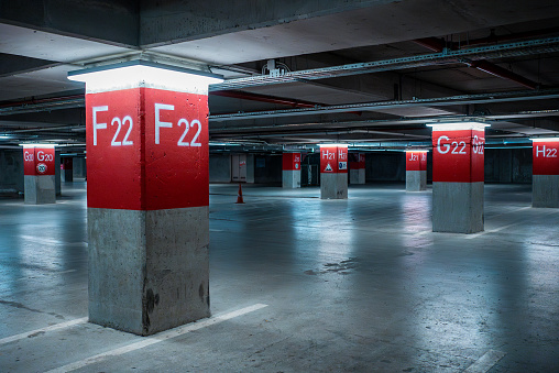 The parking lot of a building divided by red columns.