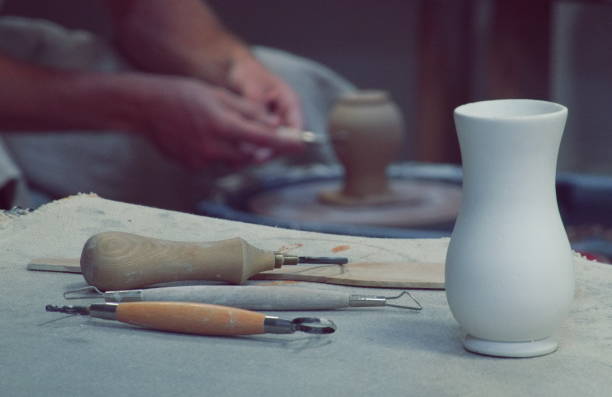 istock Workshop. Art Studio. Potter at work. White Clay Vase on Table. Potter's tools. Potter's hands on a Background. Filtered Photo 1884469050