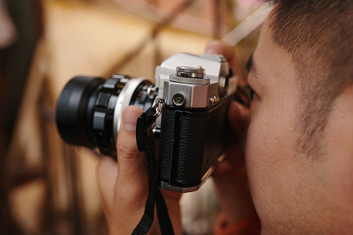 Closeup image of photographer looking through viewfinder of vintage camera