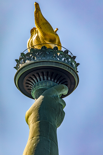 Photo of the Statue of Liberty hand holding her torch on a sunny day in Manhattan, known as the lady of New York City USA.