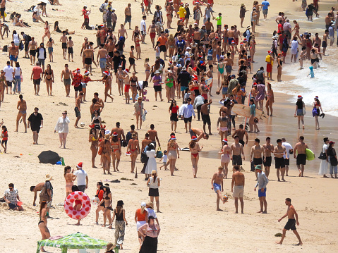 Bondi Beach in the Eastern Suburbs of Sydney on Christmas Day 2023 attracts a multicultural crowd of locals and tourists.  This image was taken from the southern end of the beach looking north on a sunny and hot afternoon on 25 December 2023.