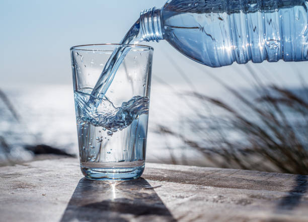 istock Pouring water into a glass from plastic bottle. Nature background. 1884520641