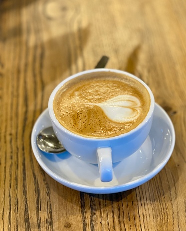 Cappuccino coffee in white cup on Wood table