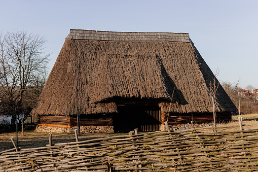 Kourim, Czech Republic, 17 December 2023: Traditional village wooden timbered barn with low walls and steep thatched roof in winter, historic country style architecture, open air ethnographic museum