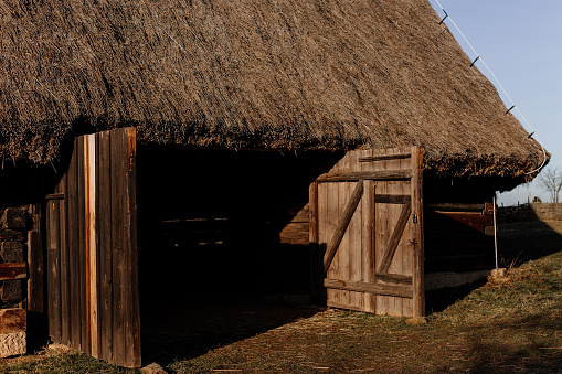 Kourim, Czech Republic, 17 December 2023: Traditional village wooden timbered barn with low walls and steep thatched roof in winter, historic country style architecture, open air ethnographic museum