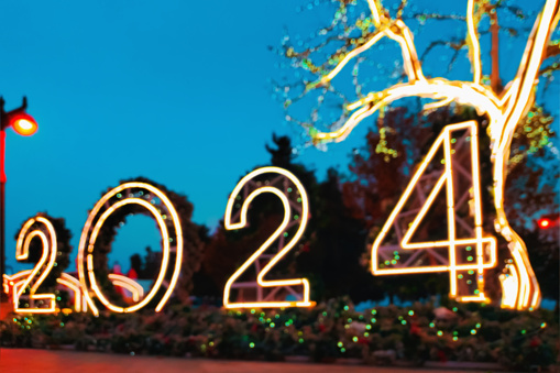 Installation with light bulbs and garlands with the numbers 2024 and glowing trees in a city park, timed to celebrate the arrival of the new year.
