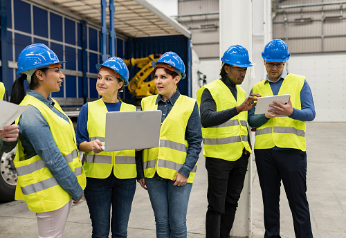 Factory workers or engineer worker working for check and analyze newly arrived goods using laptop and digital tablet, teamwork and synergy concept