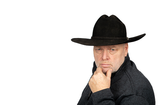 Middle Aged Caucasian Man in Cowboy Hat Deep in Thought on White Background - Reflective, Introspective, and Farmer Contemplative Concept.