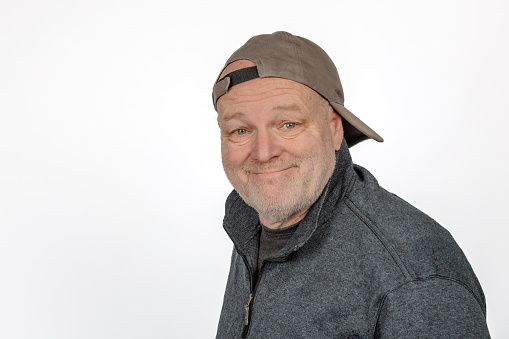 Cheerful Caucasian Middle-aged Man in Backward Baseball Cap on White Background.