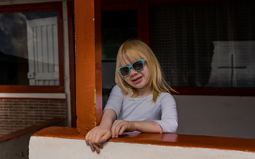 portrait of albino girl smiling and wearing sunglasses while wearing a dress and looking at the camera