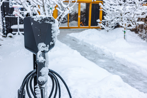 Close-up view of an electric vehicle charging station in a private parking area on a winter day. Sweden.