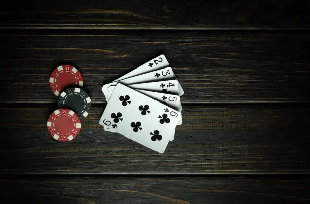 Photo of Popular poker game with straight flush winning combination. Cards with chips on a black vintage table in a poker club. Free black space for ads.