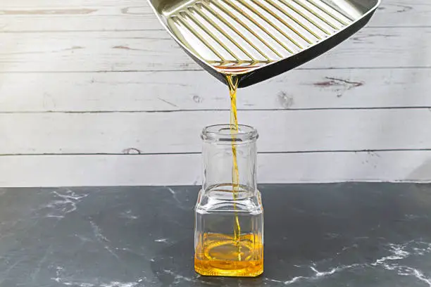 Pour the used cooking oil from the pan into the glass bottle. Old or used cooking oil can be recycled into biodiesel.