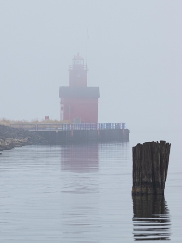 Lighthouse in the fog on the edge of Lake Michigan at dawn.